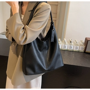 Detailed close-up of large black leather tote bag with litchi grain and soft texture
