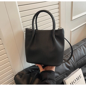Detailed close-up of a black pleated leather bucket bag with top handle and strap