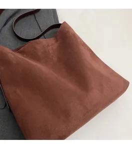 Detail of soft brown suede texture and leather strap on large capacity tote bag