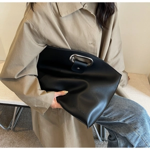 Detail of black matte leather handbag with silver oval handle and embossed logo