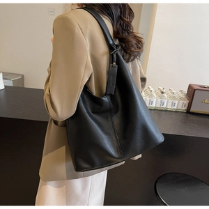 Detail of a large black lychee leather hobo bag with sleek shoulder strap and tag