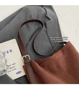 Detail view of brown suede bucket bag featuring adjustable leather strap and metal buckle