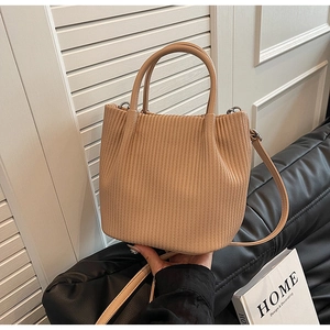 Close-up of beige pleated bucket bag on a leather sofa with chic lifestyle decor