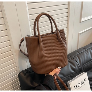 Close-up of dark brown pleated bucket bag with dual handles and detailed texture