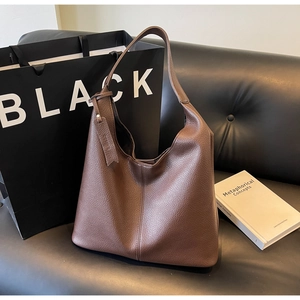 Close-up of large brown leather tote bag with lychee texture and decorative hangtag