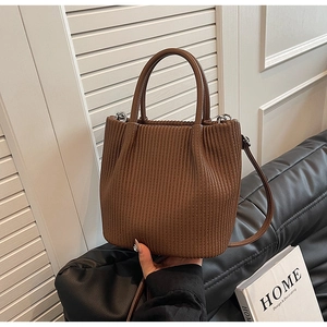 Detail of dark brown pleated bucket bag with dual handles and smooth leather texture