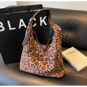 Detail of leopard print tote bag with brown leather handles on a leather sofa