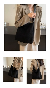 Detail view of large black suede tote bag showing texture and minimalist shoulder strap