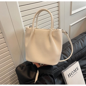 Detail of pleated cream corduroy bucket bag texture with shoulder strap and handles