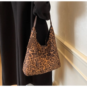 On-shoulder view of large leopard print hobo bag paired with a black winter coat