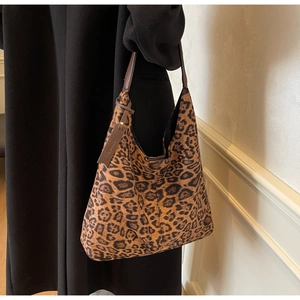 Detail of leopard print tote bag featuring brown leather straps and metal rivets decoration