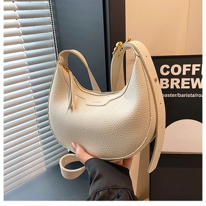 Close-up of white crescent bag showing premium lychee texture and gold hardware