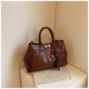 Macro shot of brown retro PU leather handbag with silver lock and tennis charm detail