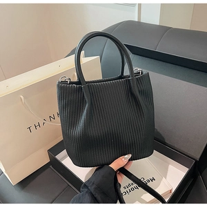 Close-up of black pleated bucket bag with vertical textured folds and smooth leather handle
