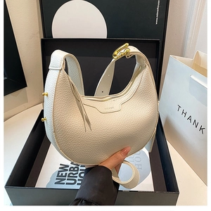 Detail of white half moon leather bag with gold hardware and luxury gift packaging