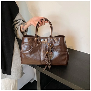 Close-up of vintage brown leather tote bag with metal twist lock and fringe detail