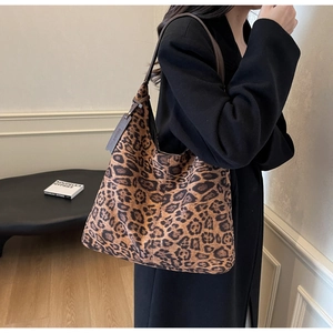 Detail of leopard print tote bag featuring brown faux leather straps and a decorative tag