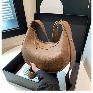 Close-up of brown litchi pattern leather half-moon bag inside a black luxury gift box