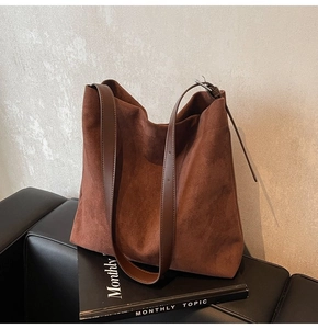 Detail of soft brown suede hobo bag texture and leather strap on a sofa background