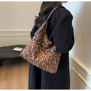 Detail view of large leopard print hobo bag with brown leather shoulder strap on model