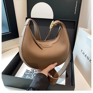 Detail of brown leather crescent bag with lychee texture and gold metal buckle