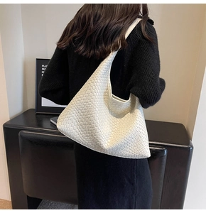 Detailed view of large white woven faux leather hobo bag worn on a model shoulder