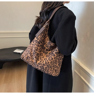 Detail of leopard print tote bag with brown leather straps shown on a model