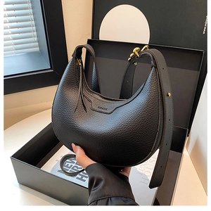 Detail of black pebble leather hobo bag featuring gold hardware and a wide shoulder strap
