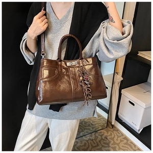 Detail of dark brown glossy tote with silver buckle and decorative Romea tassel charm