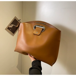 Detail of brown leather tote bag with metal handle and magnetic flap closure