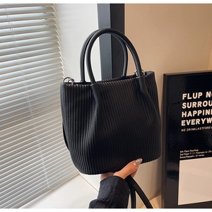 Detail of a black pleated bucket bag featuring vertical ruffles and adjustable shoulder strap