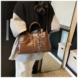 Detail view of a vintage dark brown satchel featuring gloss finish and metal twist lock