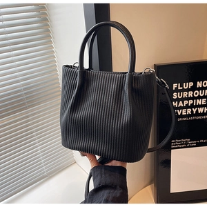 Detailed view of vertical pleated texture on black bucket bag with adjustable shoulder strap