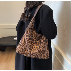 Detail view of large leopard print tote bag with brown leather strap worn by a model