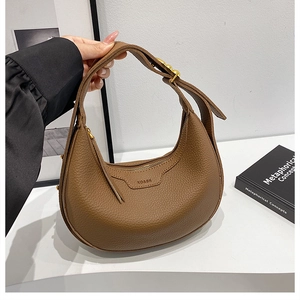 Detail view of brown lychee grain leather crescent bag with adjustable gold buckle strap