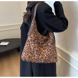 Leopard print tote bag with brown leather straps shown worn by model in a minimalist setting