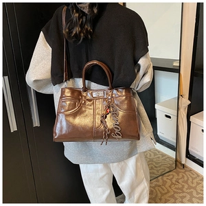 Detail of dark brown metallic crossbody tote with shiny finish and retro metal clasp