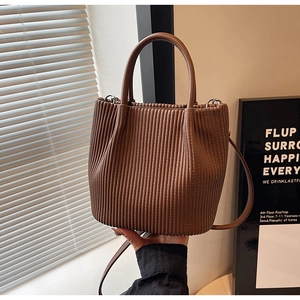 Detail of dark brown pleated bucket bag with textured vertical folds and sturdy top handle