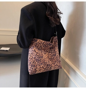 Detail of large leopard print suede shoulder bag styled with a minimalist black coat