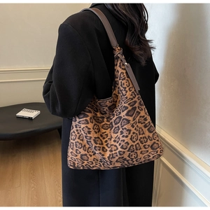 Detailed view of leopard print tote bag styled with a black coat in a chic indoor setting