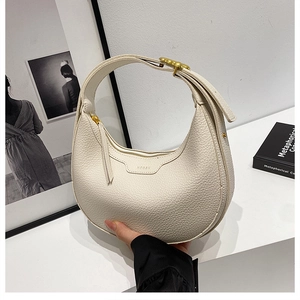 Close-up of off-white crescent saddle bag featuring lychee grain leather and gold buckle