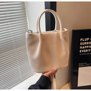 Detail of white corduroy bucket bag texture with top handles and adjustable shoulder strap