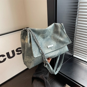 Minimalist washed denim tote bag with silver chain strap and metal logo on the front flap