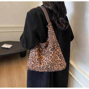 Detail of leopard print tote bag with brown leather strap and decorative pendant tag
