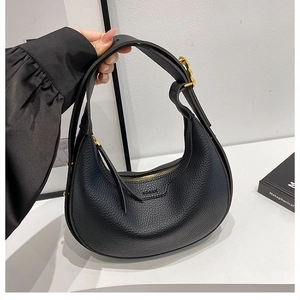 Detailed view of black litchi pattern leather texture on a crescent moon saddle bag