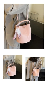 Detail of pink lychee leather bucket bag featuring a decorative silk scarf on the handle