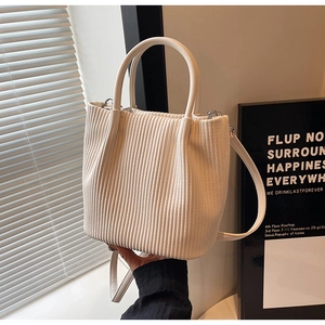 Detailed shot of cream pleated bucket bag texture with silver buckles and long strap