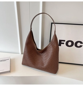 Detail of a brown woven leather tote bag featuring the classic Intrecciato craft pattern