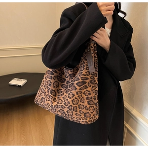 Detailed view of leopard print tote bag featuring a decorative brown leather tassel charm