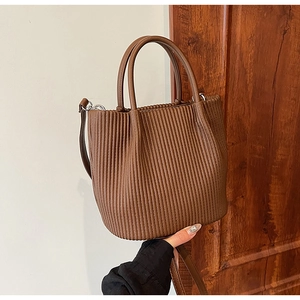 Detail of dark brown pleated leather bucket bag with cylindrical handles and strap